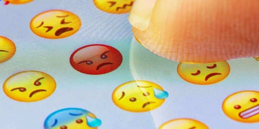 Person pointing to an angry emoji on a device