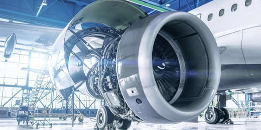 Aircraft jet engine undergoing maintenance inside an aviation hangar.